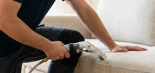 Professional upholstery cleaner deep-cleaning a fabric sofa with a handheld extraction tool, San Diego, CA.